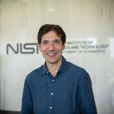 Photo of man in blue shirt with NIST logo in background