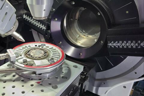 Scientific device has a circular opening; a circular metal "wafer" sits outside it on a platform. 