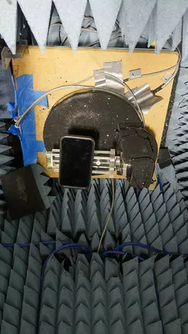 Test setup shows smartphone on a holder surrounded by wiring and pointed insulation material. 