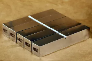 Five NIST certified reference Charpy specimens. Each specimen is labeled with the NIST logo.