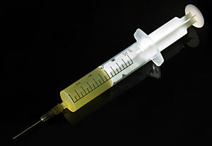 black background. syringe filled with yellow liquid