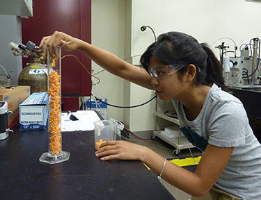 High school student Jessica Young checking the packing density of random aggregates of plastic spheres in a cylinder. 