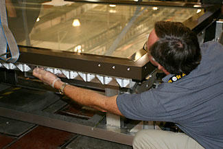 NIST technician Dana Strawbridge bolts the top frame of the map encasement to its base during a test sealing of the encasement prior to shipping to the Library of Congress.