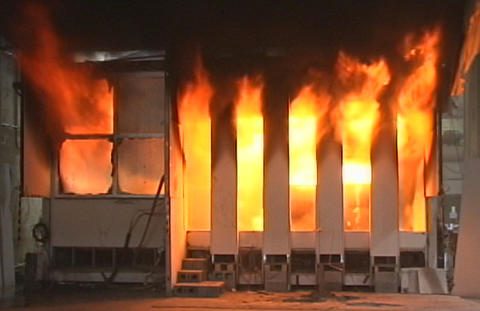 WTC Fire Experiment #6 showing room completely enveloped in flames and showing failure of two glass panels on left.