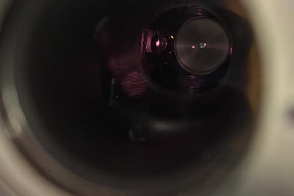 View through a circular opening into a dark interior. A red dot floats in the darkness. 