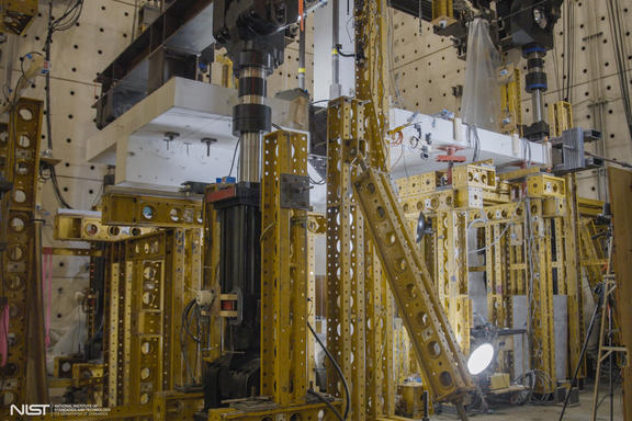 Horizontal concrete slab is visible in a forest of scaffolding and equipment in a large indoor space. 