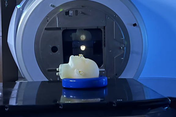 A model of a human head lies face up on the platform of an MRI machine. 