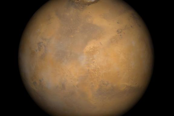 Color-enhanced photo of Mars shows the planet with patches of orange and brown. 