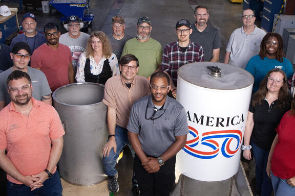 A group of people around a cylindrical time capsule