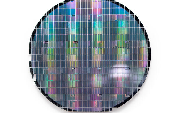 Circular sheet holds hundreds of tiny metallic rectangles reflecting rainbow colors. 