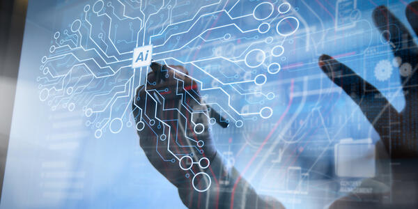 Hands draw on a transparent screen with circuits making the shape of a brain and "AI" written in the center. 