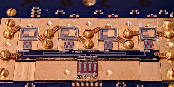 Circuit board with various square chips and gold screws. Small letters in the center say: NIST True Bq.