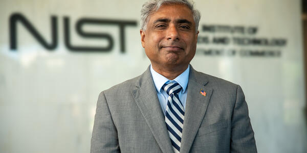 NIST director standing in front of the NIST logo