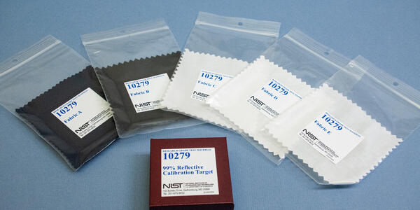 Five fabric swatches in clear plastic bags labeled 10279 are arrayed around a box labeled 99% Reflective Calibration Target. 