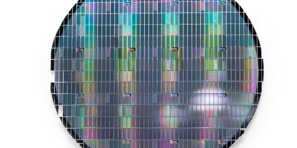 Circular sheet holds hundreds of tiny metallic rectangles reflecting rainbow colors. 