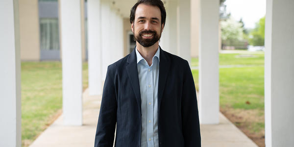 Corey Stambaugh poses smiling outdoors on the NIST campus.