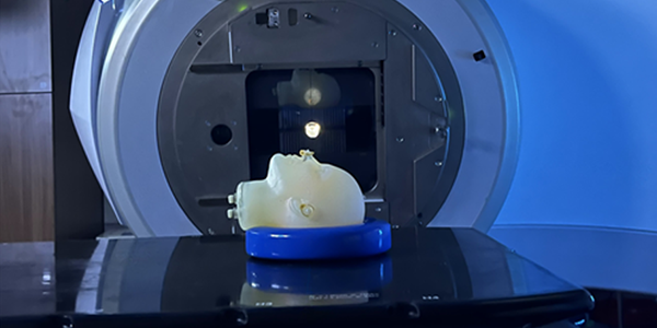 A model of a human head lies face up on the platform of an MRI machine. 