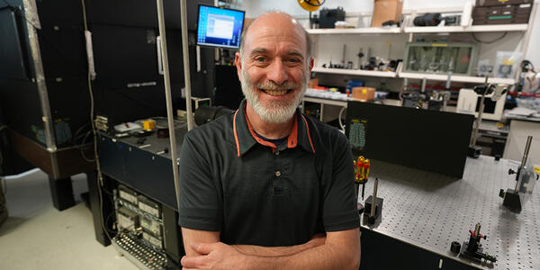 A man poses smiling in a laser laboratory.