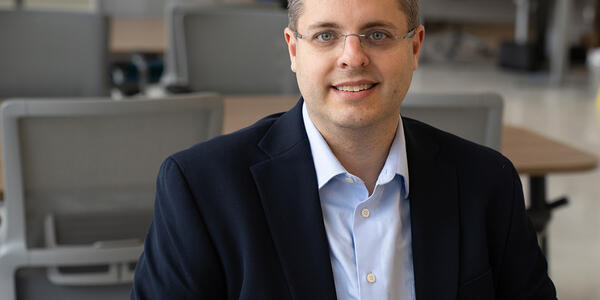 Andrew Regenscheid poses sitting at a table in the NIST library. 