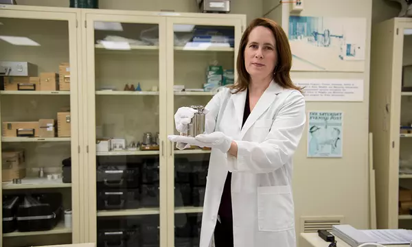 Elizabeth Gentry holding a kilogram test weight in the weights and measures training lab