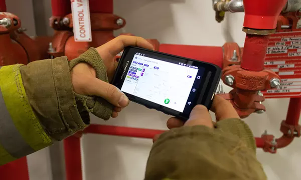 firefighter holding a phone with an app pulled up on the screen