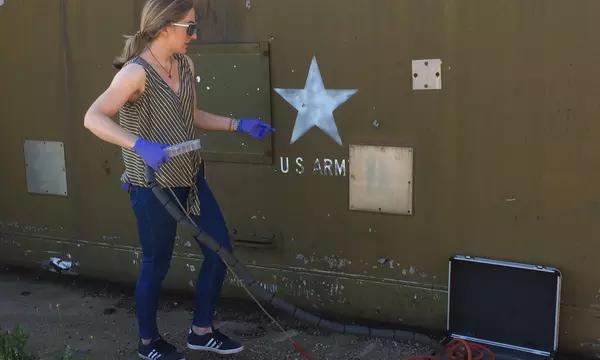 Woman in safety goggles operates an instrument housed in an aluminum briefcase