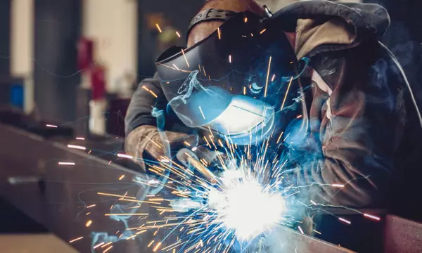 Welder working on metal in a manufacturing facility