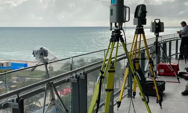 Equipment stands on tripods on a balcony with the beach and sea in the background.