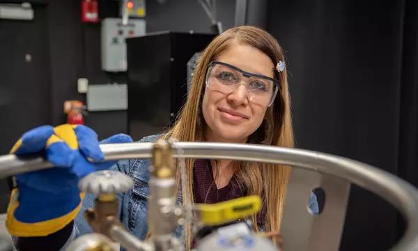 Maria Munoz poses in the lab, wearing safety goggles and heavy gloves. 