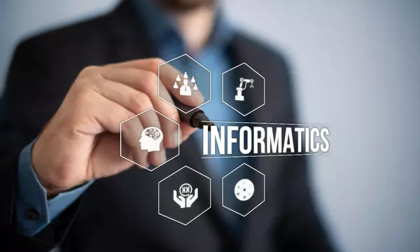 Technology related symbols with the word informatics, superimposed on a background with a man holding a pen.
