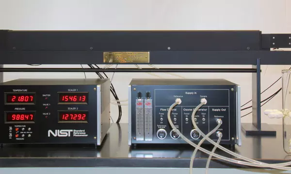 ]:  Photograph of instrumentation consisting of a box with digital displays, another box with tubes and knobs, and a third longer box with gas cell.