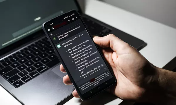 methods of data collection in research project In front of a laptop computer, a hand holds a cell phone that has a conversation with generative AI on the phone screen.