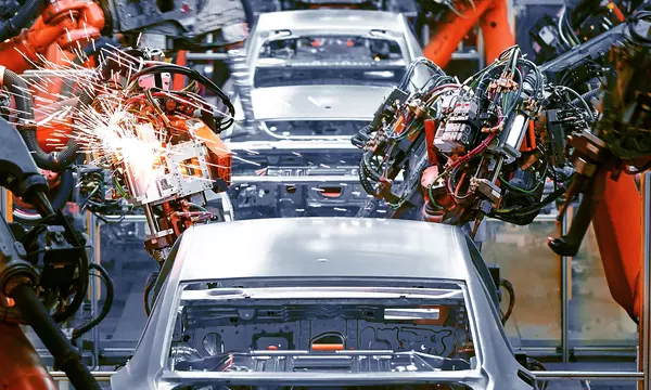 Cars on an assembly line with robotic arms doing work on them. Credit: Shutterstock/Jenson