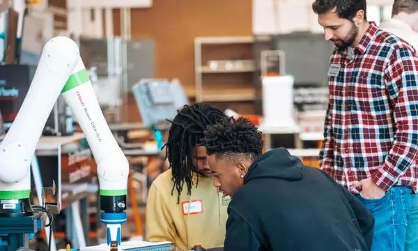 Three men work on a robot arm
