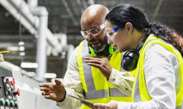 A man and woman work at a manufacturing dashboard.