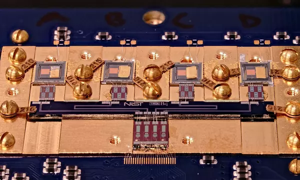 Circuit board with various square chips and gold screws. Small letters in the center say: NIST True Bq.