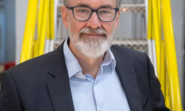 Ron Jones poses for a head shot on a yellow metal stairway