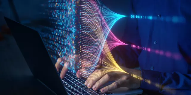 Hands rest on a laptop keyboard beneath a floating overlay of computer code and connecting lines.