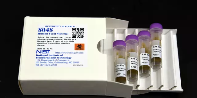 A white box labeled "8048 Human Fecal Material" lies open, with a tray of four plastic vials pulled out. 