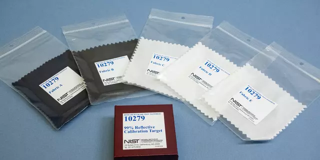 Five fabric swatches in clear plastic bags labeled 10279 are arrayed around a box labeled 99% Reflective Calibration Target. 