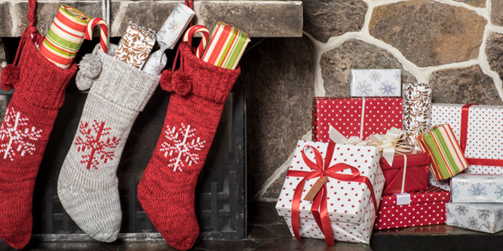 stockings stuffed with gifts hung on a fireplace mantle with wrapped presents