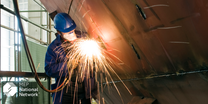 man welding the side of a boat