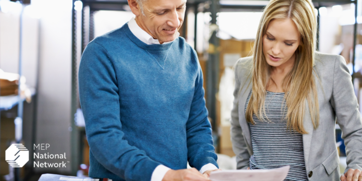 two pepole looking at papers in a manufacturing facility