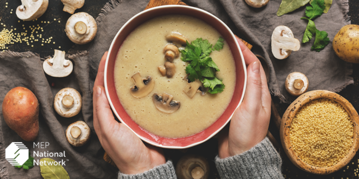 woman in a grey sweater holding a bowl of cream of mushroom soup
