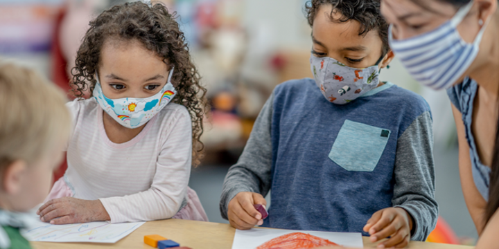 Group of children colouring while wearing masks