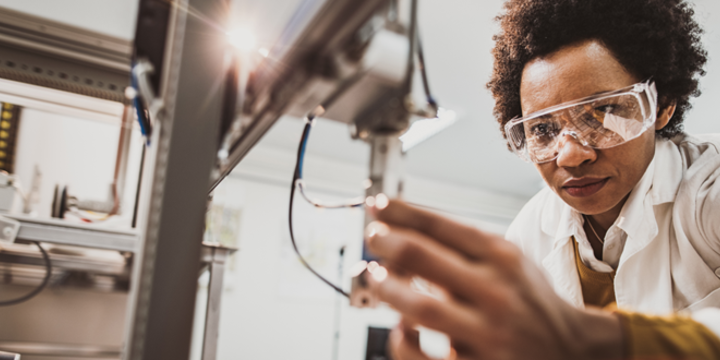 Black female engineer working on industrial machine in a laboratory