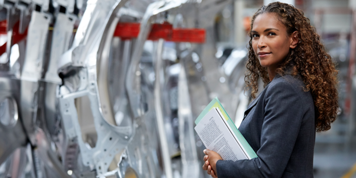 Confident manager standing by chassis in car plant