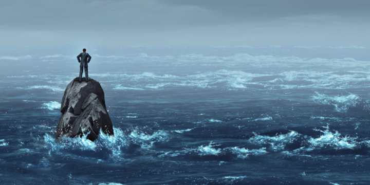 man standing on a rock weathering a storm at sea