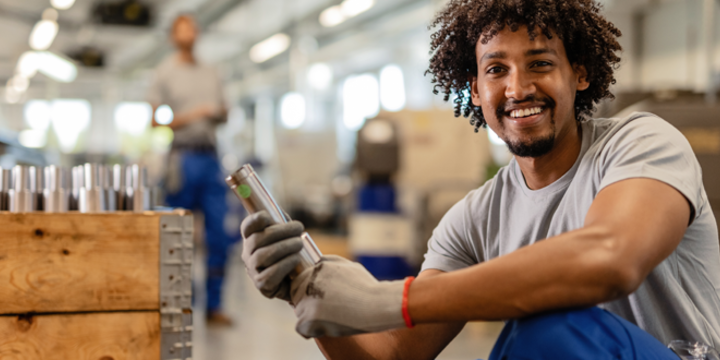 African American worker checking quality of manufactured steel parts