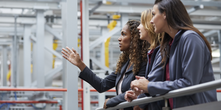 Engineers discussing at railing in car plant 